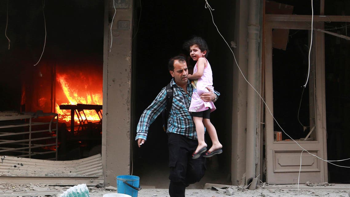 A man carrying a child runs out of a burning building at a site hit by what activists said were barrel bombs dropped by forces of Syria's President Bashar al-Assad in Aleppo's al-Shaar district July 9, 2014. (Reuters)
