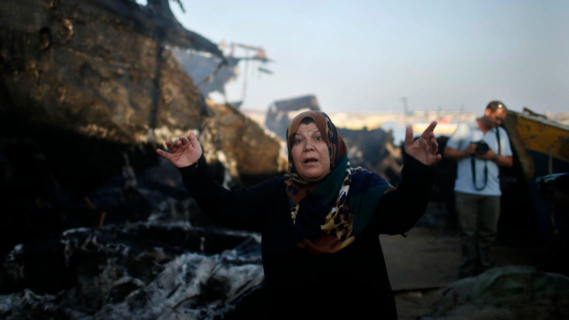 A Palestinian woman reacts in front of her son's boat, which police say was damaged in a fire that started following an Israeli naval strike, at the seaport of Gaza City July 11, 2014. (Reuters)