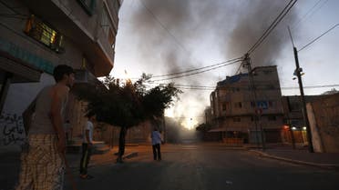 Palestinians stand looking at smoke billowing from a nearby building hit by an Israeli air strike in Gaza City on July 13, 2014. (AFP) 