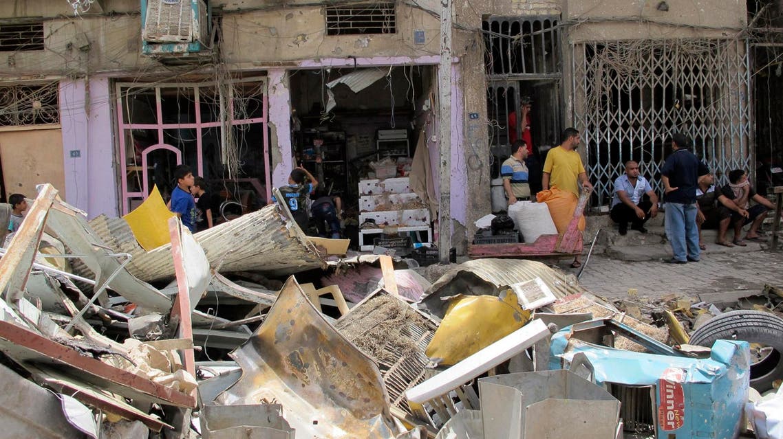 Residents look at the site of a car bomb attack in Baghdad July 14, 2014.