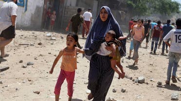 A Palestinian woman runs with her children following what police said was an Israeli air strike on a house in Gaza city July 9, 2014. 