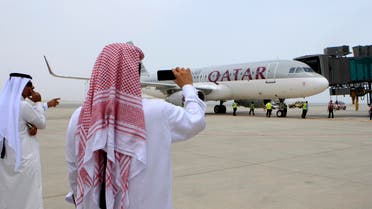 Qatari men take pictures after the Airbus A320-200 aircraft chartered by Qatar Airways landed at Doha's new Hamad International Airport 