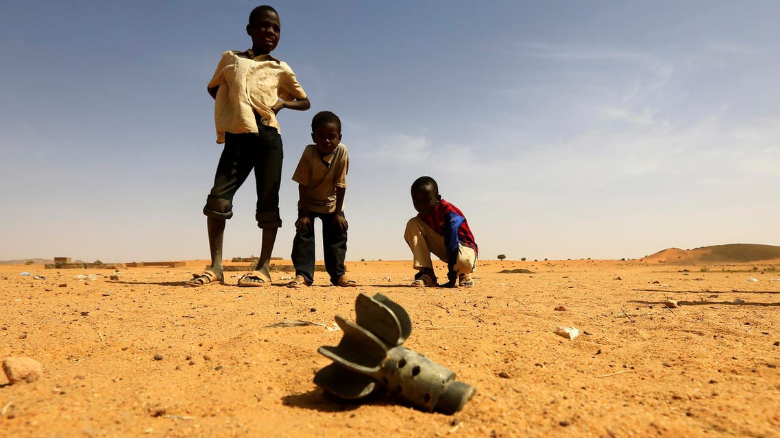 Children in Darfur examine a fallen mortar round