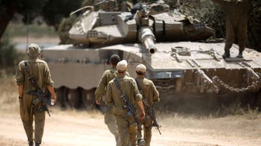  Israeli soldiers walk towards a Merkava tank, at an army deployment area near Israel's border with the Gaza Strip. (Reuters)