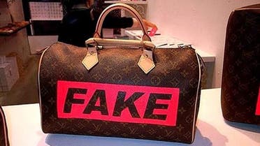 A shop assistant displays a fake Louis Vuitton bag at a store in