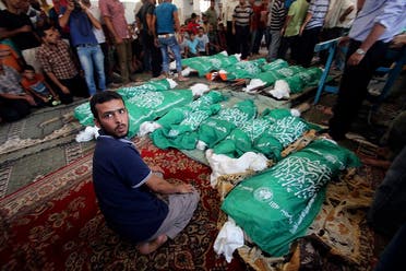 A man sits next to the bodies of Palestinians from Abu Jama'e family, who medics said were killed in an Israeli air strike that destroyed their house, during their funeral at a mosque in Khan Younis in the southern Gaza Strip July 21, 2014. (Reuters)