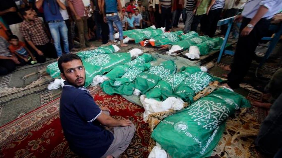 A man sits next to the bodies of Palestinians from Abu Jama'e family, who medics said were killed in an Israeli air strike that destroyed their house, during their funeral at a mosque in Khan Younis in the southern Gaza Strip July 21, 2014. (Reuters)