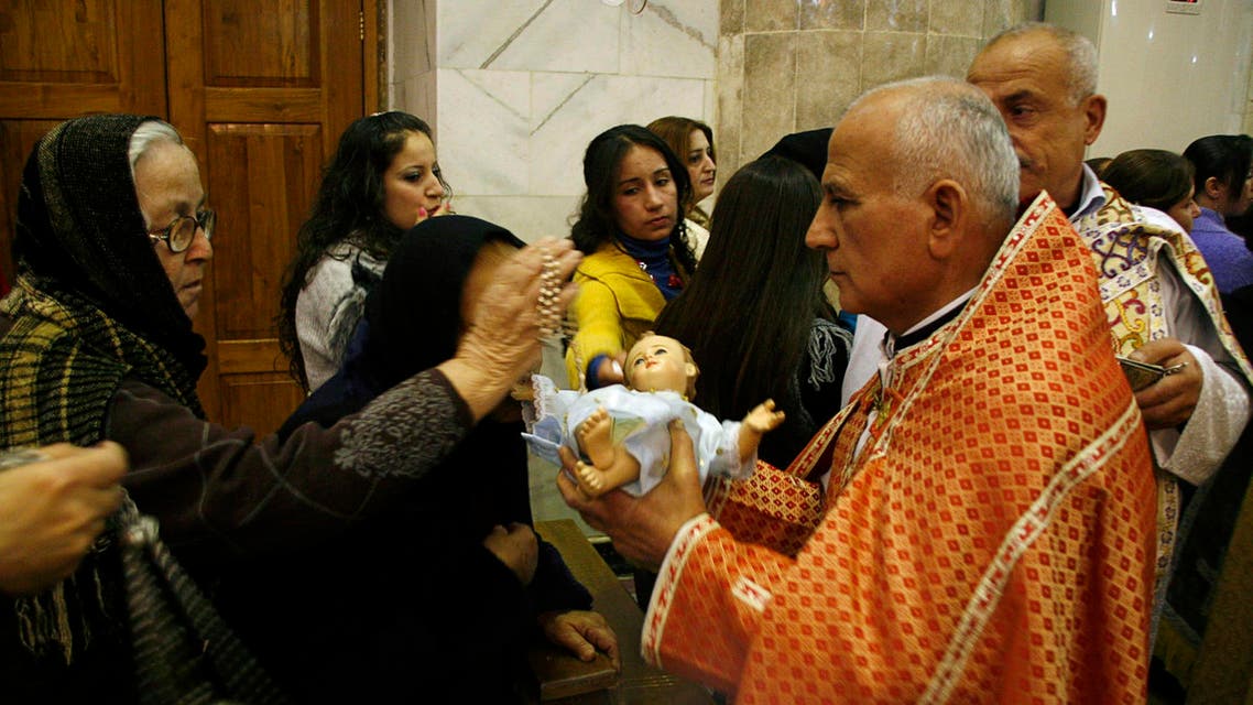 An Iraqi Christian woman crosses an effigy of baby Jesus, held by a priest, during a Christmas eve mass in a church east of Mosul, 390 km (240 miles) north of Baghdad December 24, 2010. (Reuters)
