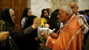 An Iraqi Christian woman crosses an effigy of baby Jesus, held by a priest, during a Christmas eve mass in a church east of Mosul, 390 km (240 miles) north of Baghdad December 24, 2010. (Reuters)