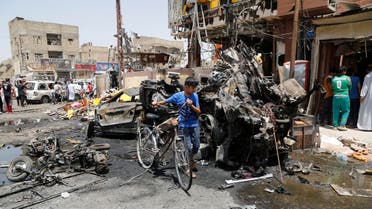 A boy walks past with his bicycle near the site of a car bomb in Baghdad's Sadr City, August 1, 2014.