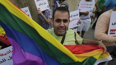 A protester waves a gay pride flag as others hold banners during an anti-homophobia rally in Beirut on April 30, 2013. (AFP) 