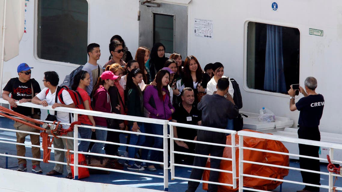 Filipino nationals pose for photos with a crew member on the deck of the MV Bridge after it arrived from Libya in Valletta's Grand Harbour August 15, 2014.