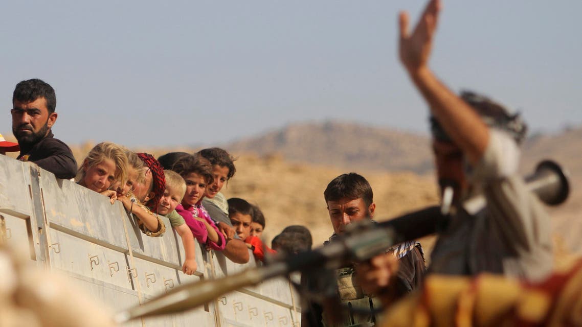 A Yazidi fighter who recently joined the Kurdish People's Protection Units (YPG) gestures while securing a road in Mount Sinjar in northern Iraq for displaced people from the Yazidi religious minority fleeing violence from forces loyal to the Islamic State in Sinjar town, as they make their way towards Newrooz camp in Syria's al-Hasakah province August 13, 2014. Reuters