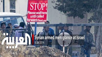 Syrian armed men glance at Israel
