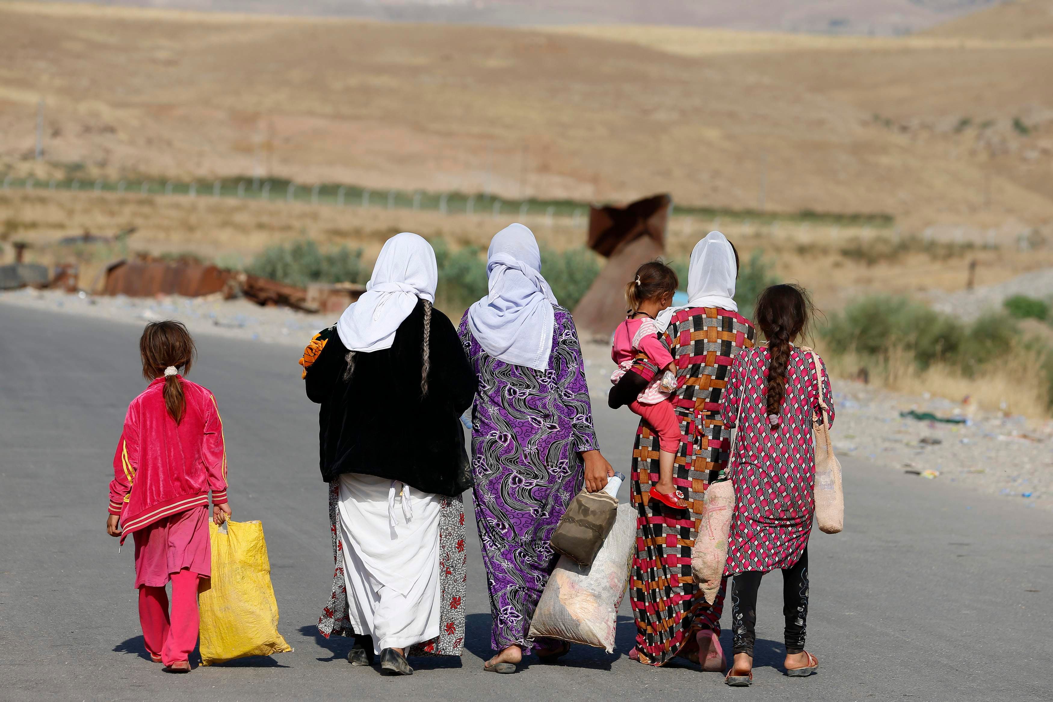 Women and children from the minority Yazidi sect, fleeing the violence in the Iraqi town of Sinjar, walk to a refugee camp after they re-entered Iraq from Syria at the Iraqi-Syrian border crossing in Fishkhabour, Dohuk province, August 14, 2014. reuters