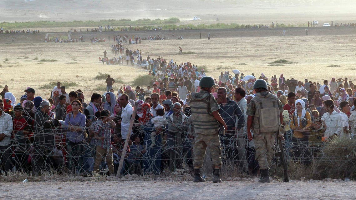 Turkish soldiers stand guard as Syrians wait behind the border fences near the southeastern town of Suruc in Sanliurfa province, September 18, 2014. (Reuters)