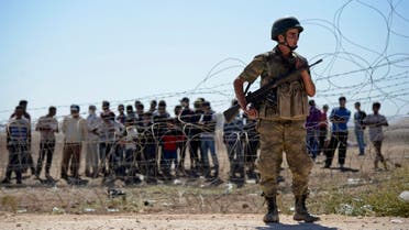 A Turkish soldier stands guard as Syrian Kurds wait behind the border fence near the southeastern town of Suruc in Sanliurfa province, September 21, 2014. (Reuters)