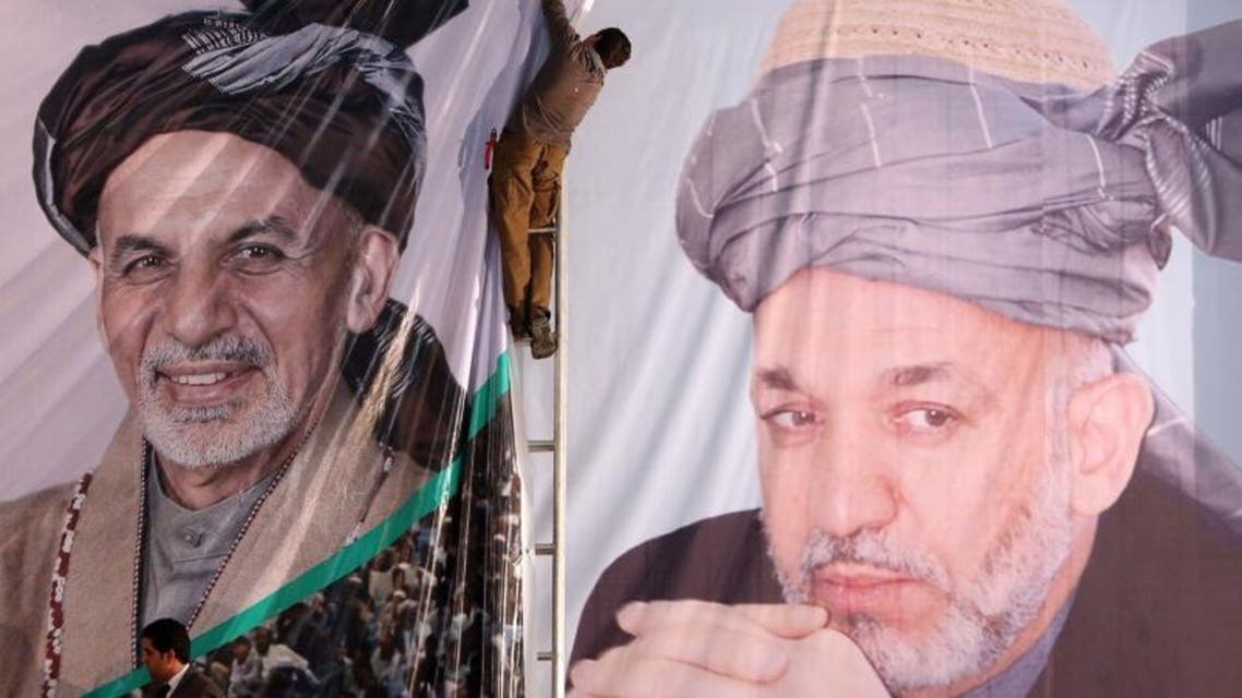 An Afghan boy prepares a banner of Afghan president-elect, Ashraf Ghani Ahmadzai (L), next to a banner of outgoing President Hamid Karzai. (Courtesy: AP)