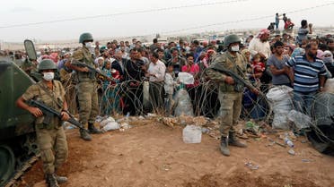 Turkish soldiers stand guard as Syrian Kurdish refugees wait behind the border fences to cross into Turkey near the southeastern town of Suruc in Sanliurfa province September 27, 2014.  (Reuters)