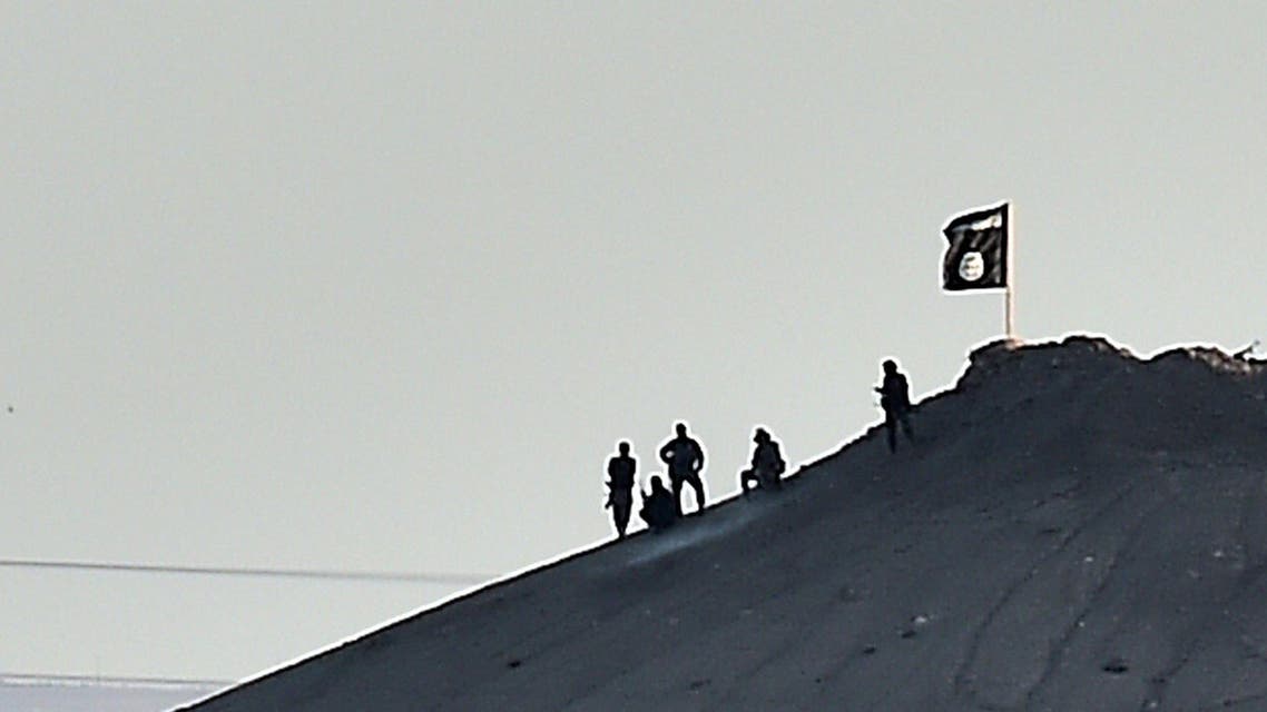 ISIS militants stand next to an ISIS flag atop a hill in the Syrian town of Ain al-Arab, known as Kobane. (AFP)