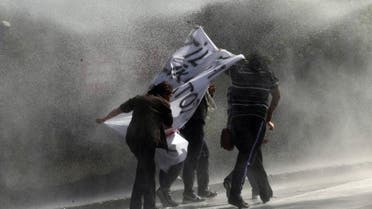  Demonstrators hold a banner as as they are sprayed by a water cannon during clashes with riot police outside of the Middle Eastern Technical University (METU) in Ankara on Oct. 9, 2014. (AFP)