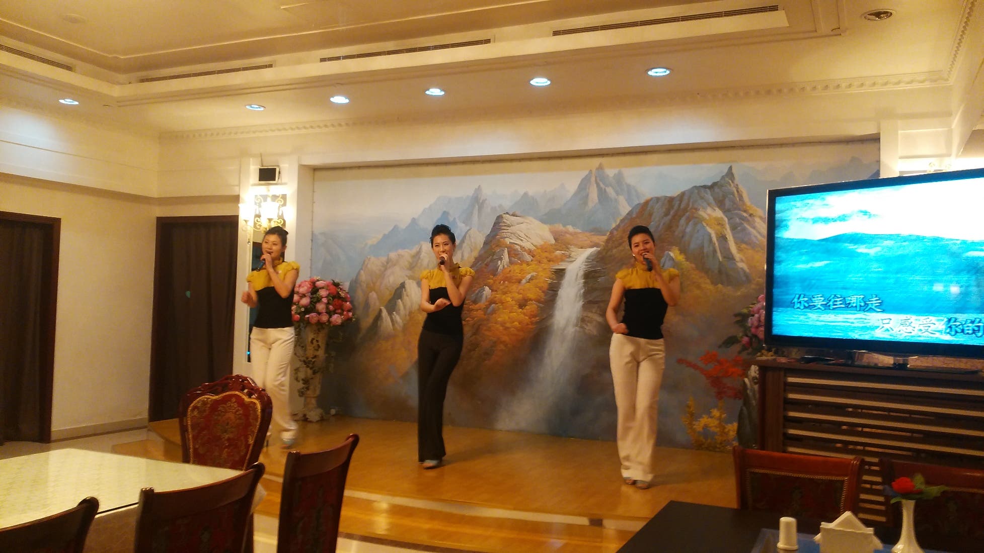 2- Dancers at the restaurant singing 'You are my superstar' with the aid of a karoke machine. All Okryu-gwan staff wear small North Korean flags pinned to their uniforms. (Al Arabiya)