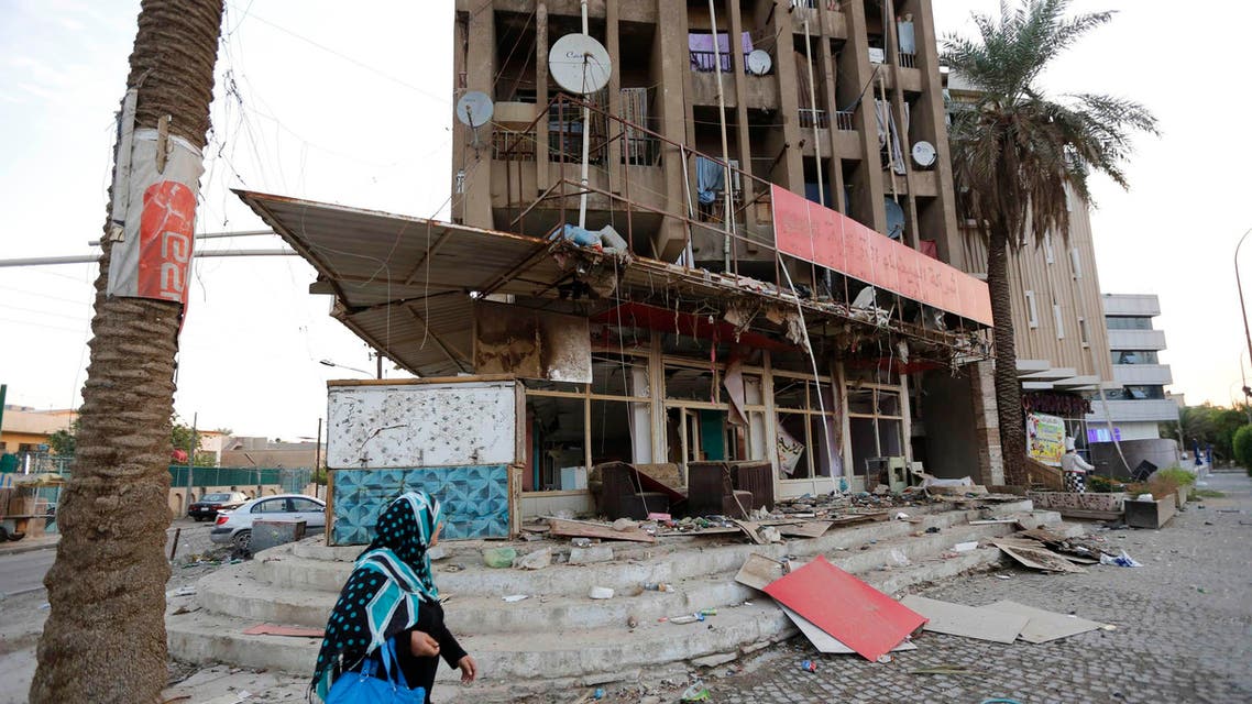 A woman walks past the site of Friday's car bomb attack in Baghdad, October 18, 2014. (Reuters)