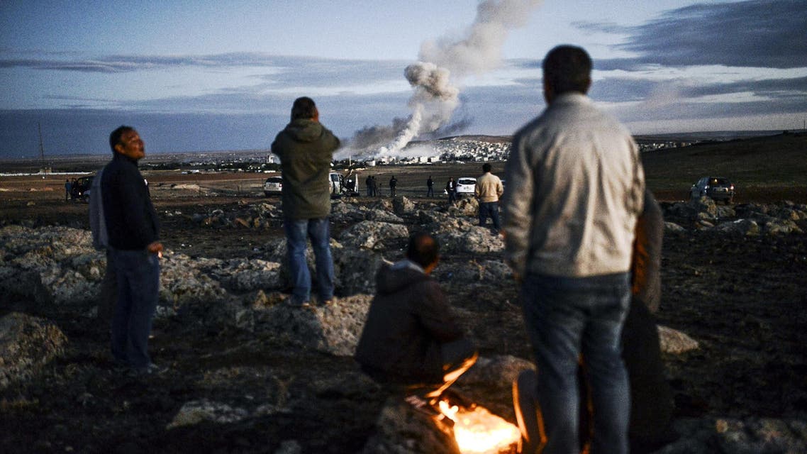 Kurdish people observe smoke rising from the Syrian town of Kobane, also known as Ain al-Arab, following an explosion as seen from the southeastern Turkish village on October 20, 2014. (AFP) 1