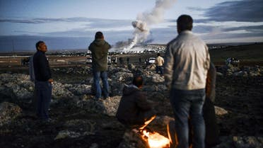 Kurdish people observe smoke rising from the Syrian town of Kobane, also known as Ain al-Arab, following an explosion as seen from the southeastern Turkish village on October 20, 2014. (AFP) 1