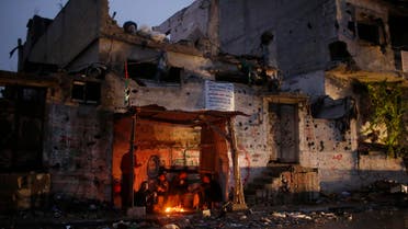 Palestinians take cover from the rain around a fire inside a makeshift shelter near damaged houses in the east of Gaza City October 19, 2014. (Reuters)