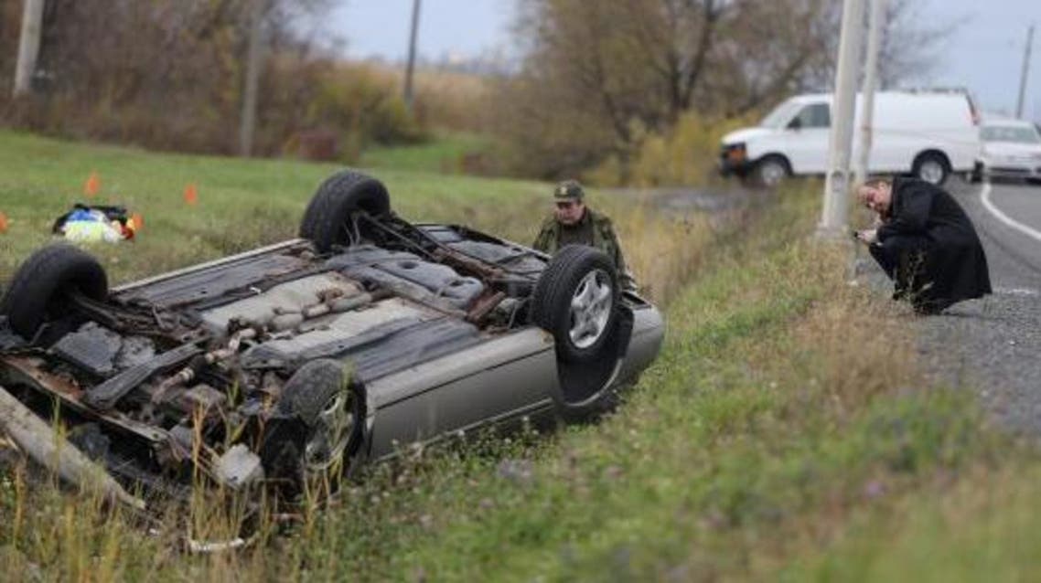 A Surete du Quebec (SQ) officer investigates an overturned vehicle in Saint-Jean-sur-Richelieu, Quebec October 20, 2014.