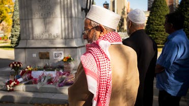 Calgary muslims take a moment after laying flowers at the cenotaph on a Canadian flag laid out for Canadian soldiers Cpl. Nathan Cirillo and Warrant Officer Patrice Vincent at Central Memorial park in Calgary, Alberta, October 24, 2014. (Reuters)