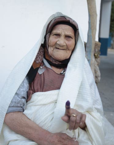 A voter raises her ink-stained finger after casting her vote at a polling station in Tunis October 26, 2014.