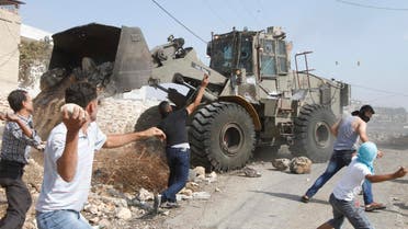 Palestinian protesters throw stones at an armored wheel loader of the Israeli army during clashes following a protest against the near-by Jewish settlement of Qadomem, in the West Bank village of Kofr Qadom near Nablus Oct. 17, 2014. (Reuters)