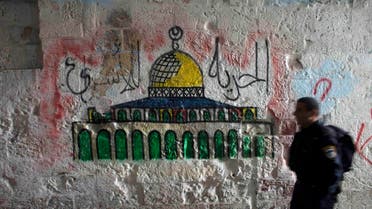 An Israeli police officer walks past a mural of the Dome of the Rock near the entrance to the compound known to Muslims as Noble Sanctuary and to Jews as Temple Mount, in Jerusalem's Old City
