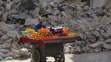 A Syrian fruit vendor waits for customers next to a damaged building on February 24