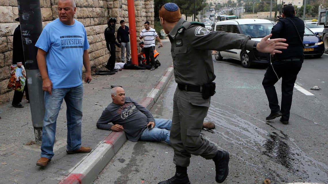 An Israeli border police officer gestures as a wounded man sits on the street after an attack by a Palestinian motorist in Jerusalem November 5, 2014. (Reuters)