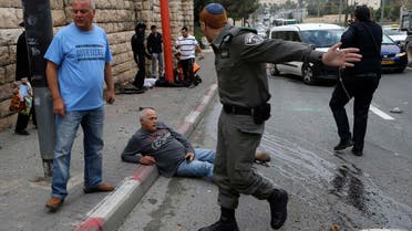 An Israeli border police officer gestures as a wounded man sits on the street after an attack by a Palestinian motorist in Jerusalem November 5, 2014. (Reuters)