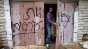  A Palestinian man inspects a door at the Hamayel family that bears Hebrew writing which reads "Death to Arabs", after an attack by suspected Jewish extremists, in a village northeast of Ramallah, on November 23, 2014. (AFP)