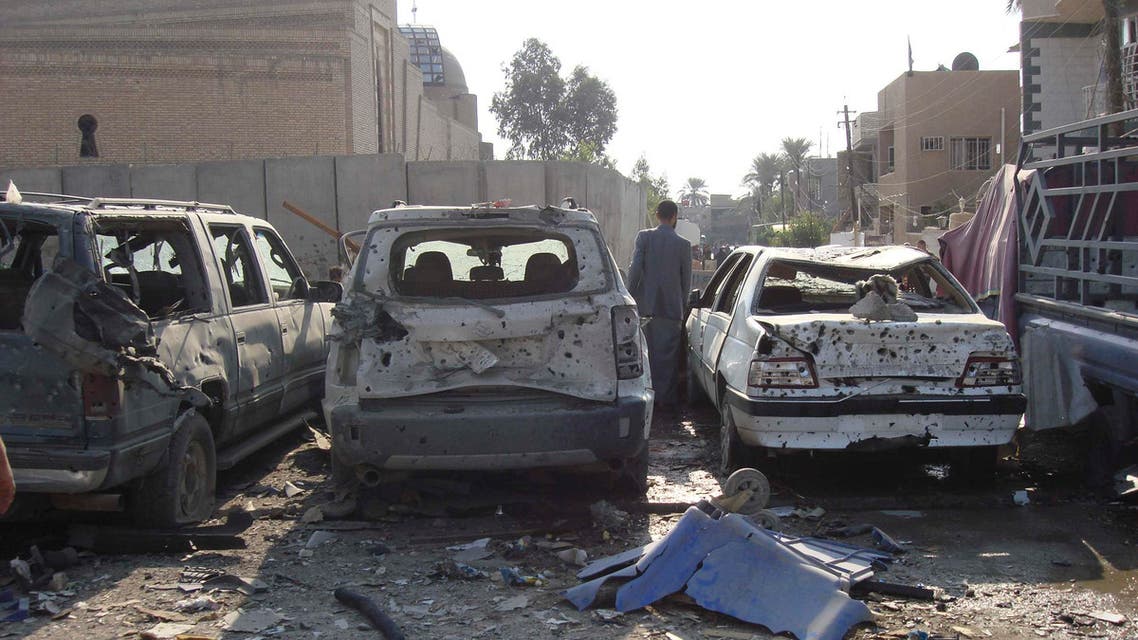 A man walks between destroyed cars at the site of a car bomb attack in Baghdad's Al-Mashtal district November 17, 2014. (Reuters)