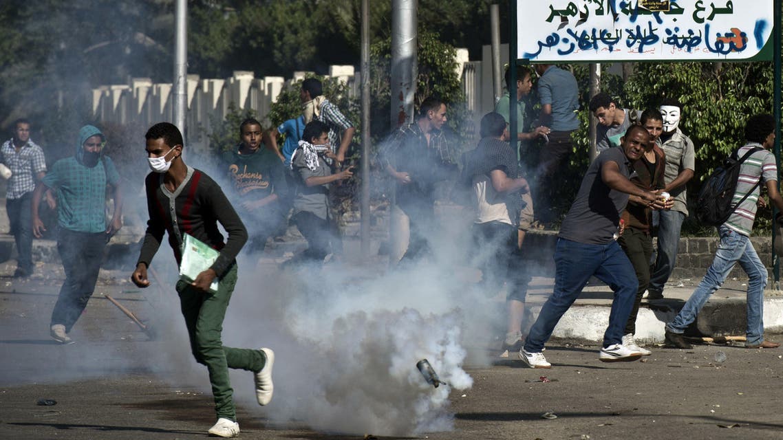 Egyptian students of al-Azhar university run for cover from a tear gas canister fired by riot police during clashes outside their university campus in Cairo AFP