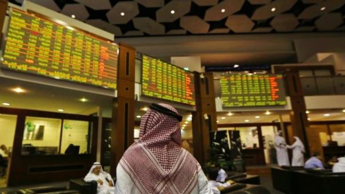 An investor looks up at screens displaying stock information at the Dubai Financial Market. (Reuters)