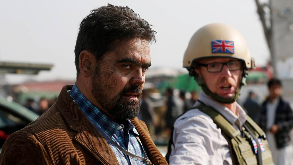 A British security official (R) escorts a survivor from the wreckage of a British embassy vehicle after a suicide attack in Kabul, Nov. 27, 2014. (Reuters)