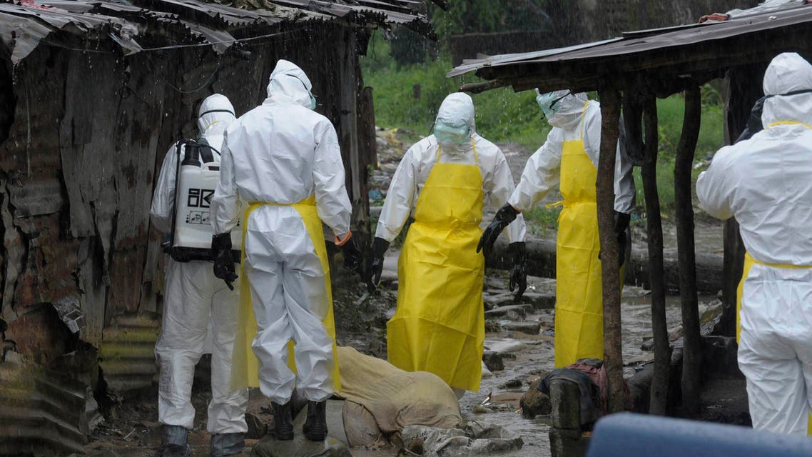 Health workers wearing protective clothing prepare to carry an abandoned dead body presenting with Ebola symptoms at Duwala market in Monrovia, in this August 17, 2014 file photo. (Reuters)