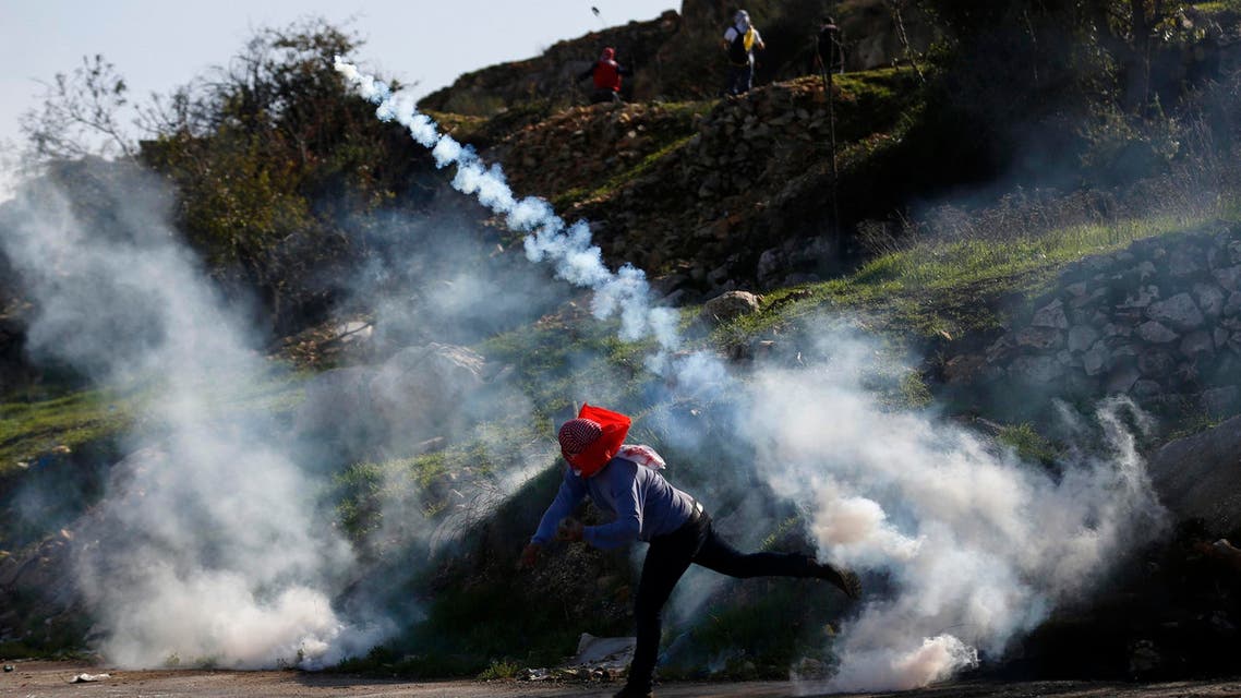 A Palestinian protester throws back a tear gas canister fired by Israeli troops during clashes near Israel's Ofer Prison, near the West Bank city of Ramallah December 13, 2014. (Reuters)