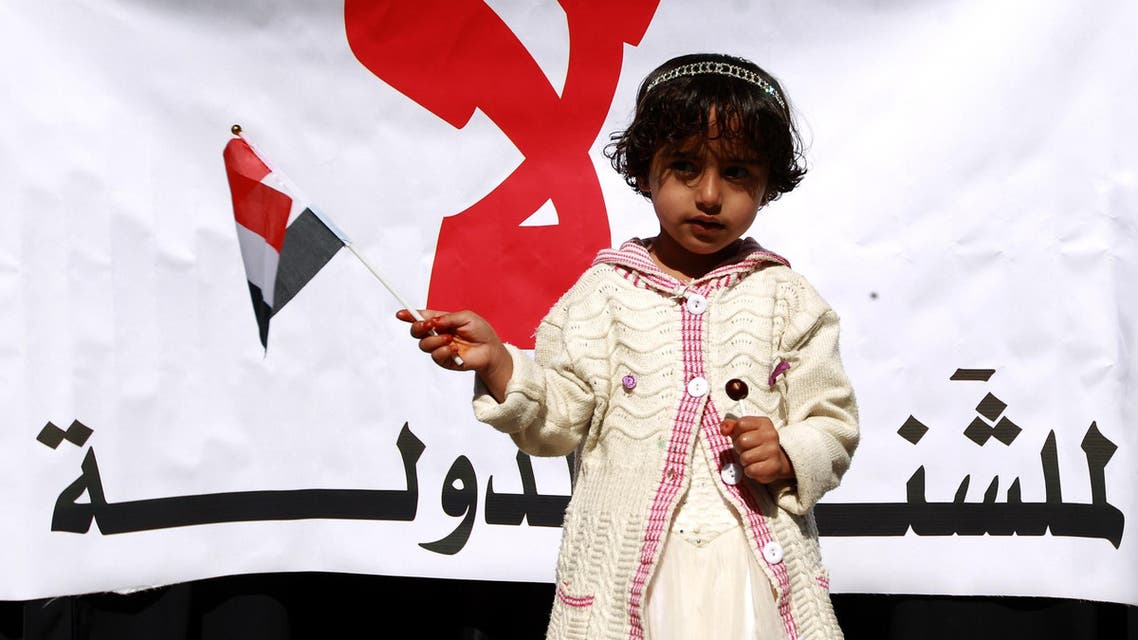 A Yemeni girl holds a national flag in front of a banner during a rally against the control of the country’s main cities by Houthi rebels on December 13, 2014. (File photo: AFP)