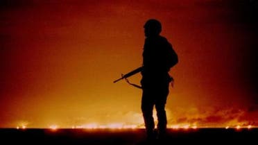 A U.S. soldier stands night guard as oil wells burn in the distance in Kuwait, just south of the Iraqi border February 26, 1991.  (Reuters)