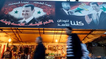 People walk past roadside stalls decorated with pictures of Syria's President Bashar al-Assad and his father, late president Hafez al-Assad (C), in the Baramkeh district of Damascus December 8, 2014. (Reuters)