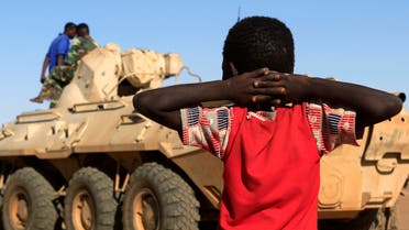 A boy looks on as a military convoy of government forces accompanying Special Prosecutor for Crimes in Darfur Yasir Ahmed Mohamed and his team arrives in Tabit village in North Darfur November 20, 2014. 