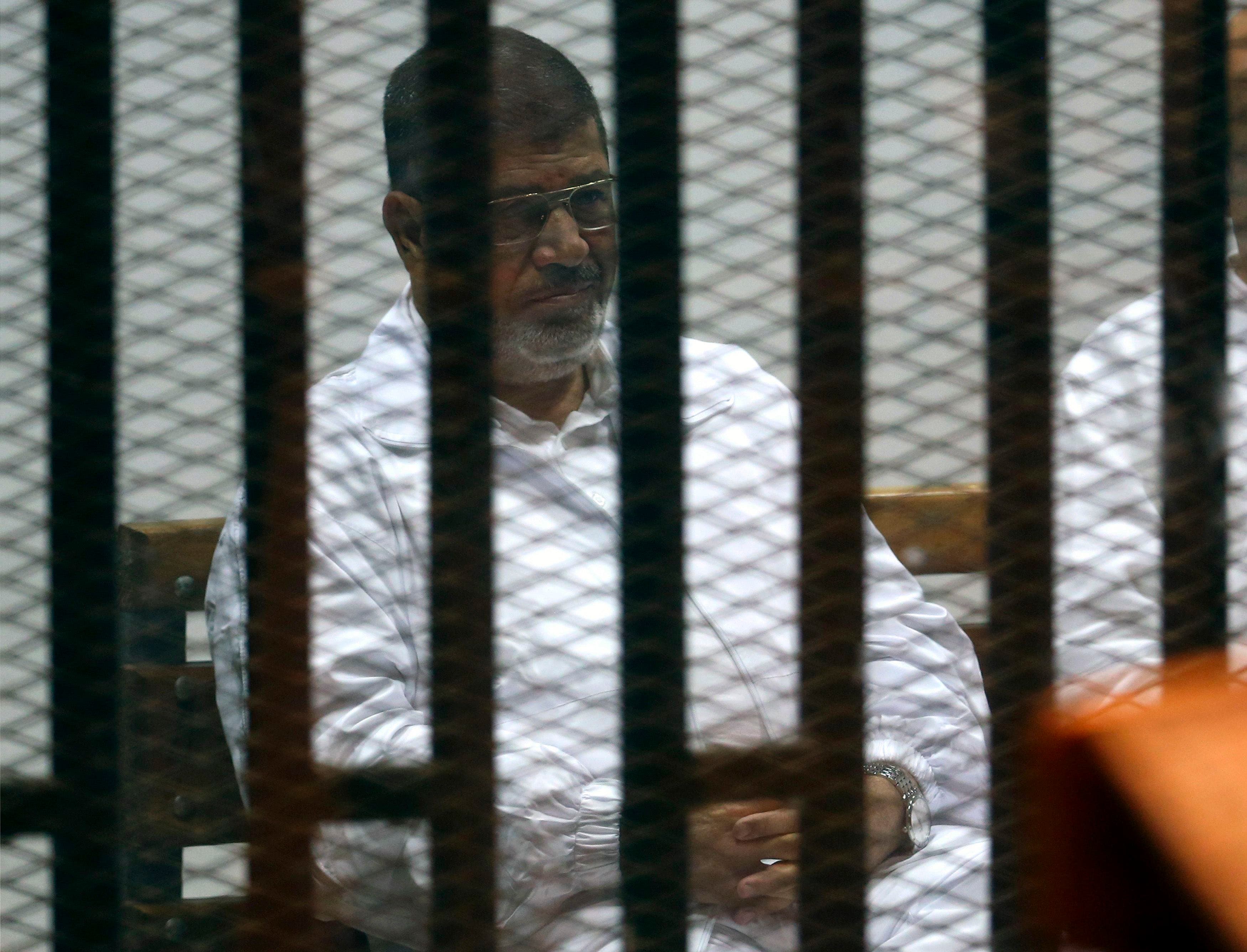 Former Egyptian President Mohamed Mursi sits behind bars with other Muslim Brotherhood members at a court in the outskirts of Cairo December 14, 2014. Egypt declared Mursi's Muslim Brotherhood a banned terrorist organization last December and Egyptian courts have sentenced hundreds of the group's members to death in mass trials that have drawn strong international criticism. Reuters